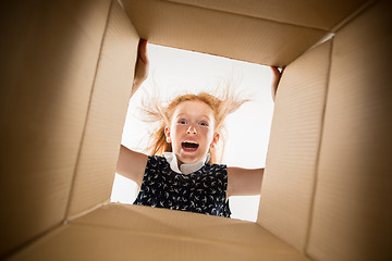 Image showing The girl unpacking and opening carton box and looking inside