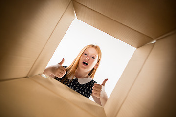 Image showing The girl unpacking and opening carton box and looking inside