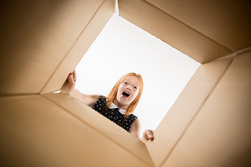 Image showing The girl unpacking and opening carton box and looking inside