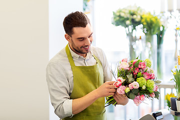 Image showing smiling florist man making bunch at flower shop