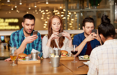 Image showing friends with smartphones at restaurant
