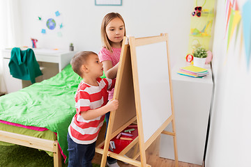 Image showing happy kids drawing on easel or flip board at home
