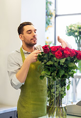 Image showing florist or seller setting red roses at flower shop