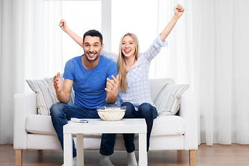 Image showing happy couple with popcorn watching tv at home