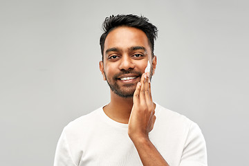 Image showing happy indian man applying cream to face