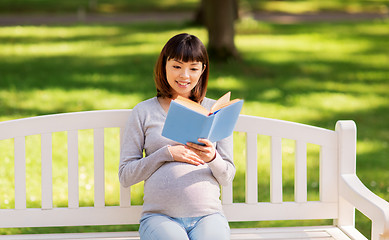 Image showing happy pregnant asian woman reading book at park