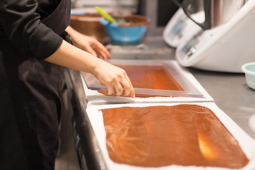 Image showing confectioner makes chocolate dessert at sweet-shop