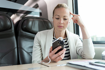 Image showing Businesswoman communicating on mobile phone while traveling by train.