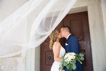 Image showing The kiss. Bride and groom kisses tenderly in the shadow of a flying veil. Artistic black and white wedding photo.