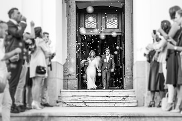 Image showing Newlyweds exiting the church after the wedding ceremony, family and friends celebrating their love with the shower of soap bubbles, custom undermining traditional rice bath