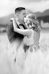Image showing Groom hugging bride tenderly and kisses her on forehead in wheat field somewhere in Slovenian countryside.