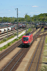 Image showing Red locomotive moving through railroad cargo marshalling station