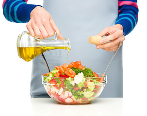 Image showing Cook is pouring olive oil into salad