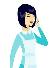 Image showing Young asian cleaner talking on a mobile phone.