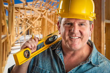 Image showing Smiling Contractor in Hard Hat Holding Level and Pencil At Const