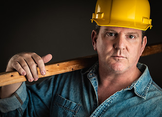 Image showing Serious Contractor in Hard Hat Holding Plank of Wood With Dramat