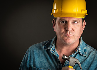 Image showing Serious Contractor in Hard Hat Holding Hammer With Dramatic Ligh