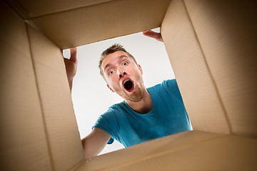 Image showing Man smiling, unpacking and opening carton box and looking inside