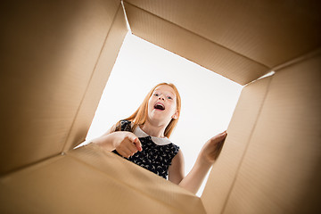 Image showing The girl unpacking and opening carton box and looking inside