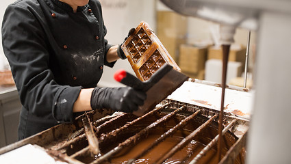 Image showing confectioner cleaning chocolate mold by spatula