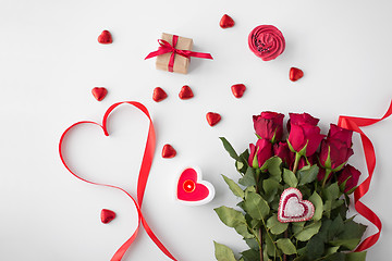 Image showing close up of red roses, gift, candies and candle