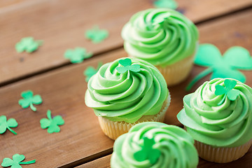 Image showing green cupcakes and shamrock on wooden table