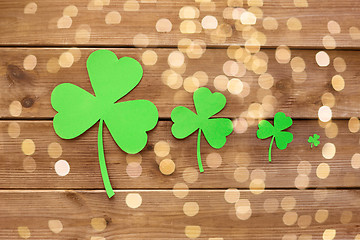 Image showing green paper shamrocks on wooden background