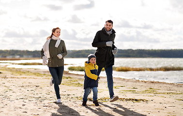 Image showing happy family running along autumn beach