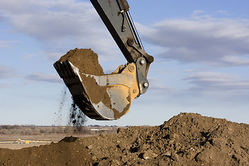 Image showing Excavator arm and scoop digging dirt at construction site