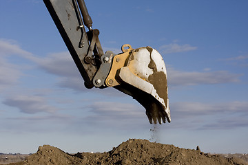 Image showing Excavator arm and scoop digging dirt at construction site
