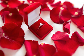 Image showing diamond ring in red velvet gift box on bed sheet