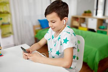 Image showing boy in earphones listening to music on smartphone