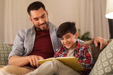 Image showing happy father and son reading book sofa at home