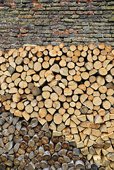 Image showing Stack of firewood on a old weathered brick wall background