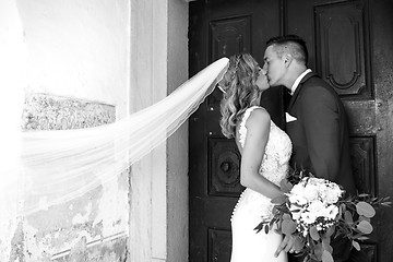 Image showing The Kiss. Bride and groom kisses tenderly in front of church portal.