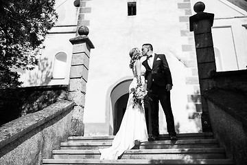 Image showing The Kiss. Bride and groom kisses tenderly on a staircase in front of a small local church.