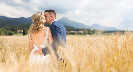 Image showing Bride and groom kissing and hugging tenderly in wheat field somewhere in Slovenian countryside.