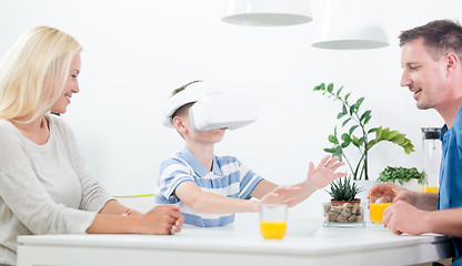 Image showing Happy caucasian family at home at dinning table, having fun playing games using virtual reality headset