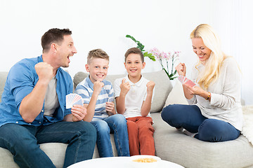 Image showing Happy family playing card game on living room sofa at home and having fun together celebrating the game winner