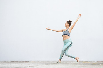 Image showing Fit sporty active girl in fashion sportswear doing yoga fitness exercise in front of gray wall, outdoor sports, urban style