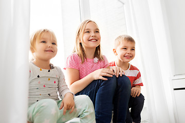 Image showing happy little kids sitting on window sill