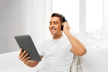 Image showing smiling man with tablet pc and headphones at home