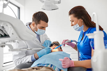 Image showing dentist treating kid teeth at dental clinic