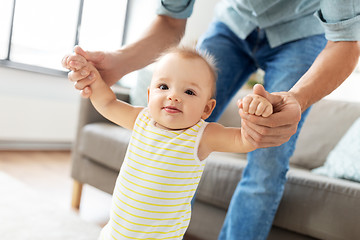 Image showing father helping baby daughter with walking at home