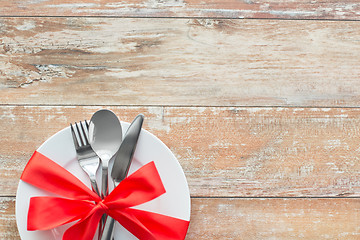 Image showing cutlery tied with red ribbon on set of plates