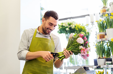 Image showing smiling florist man making bunch at flower shop