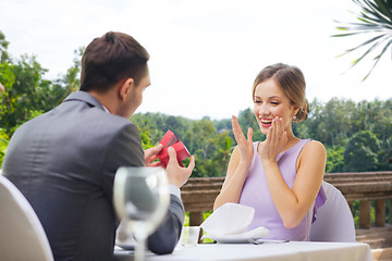 Image showing man showing woman present in red box at restaurant