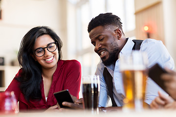 Image showing happy man and woman with smartphones at bar