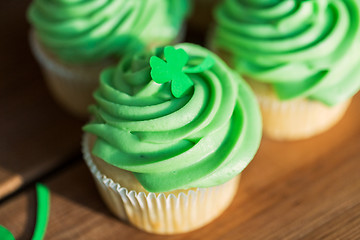 Image showing green cupcakes and shamrock on wooden table