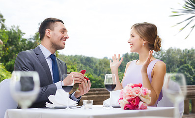 Image showing man giving woman engagement ring at restaurant